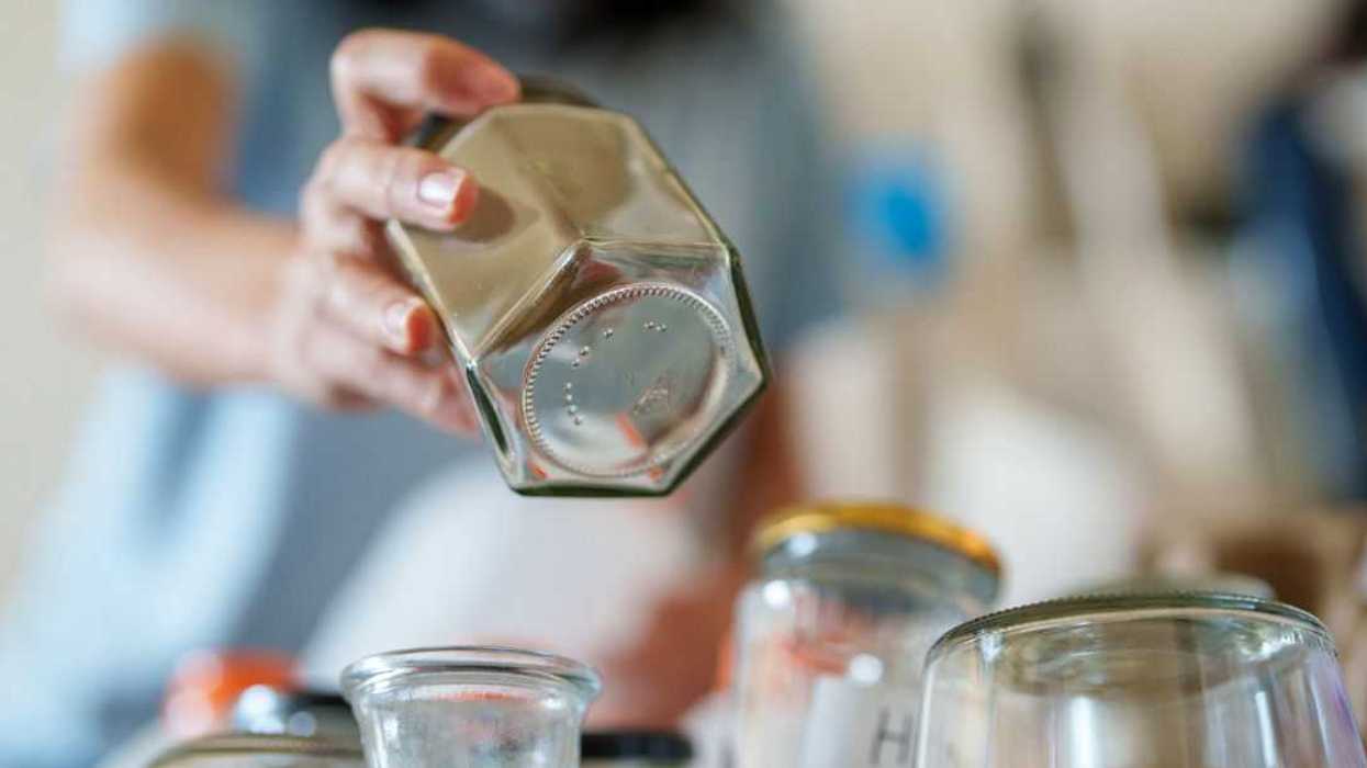 A person sorting and organizing used glass jars into a recycling bin, promoting zero-waste living and sustainable waste management at home.