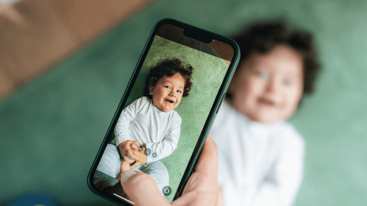 A person taking a picture of a baby with their smart phone.