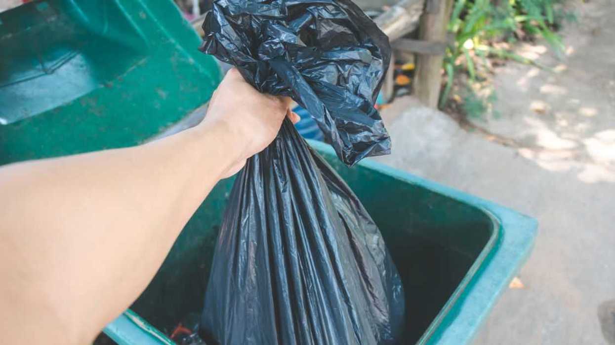 A person throws a bag of garbage away