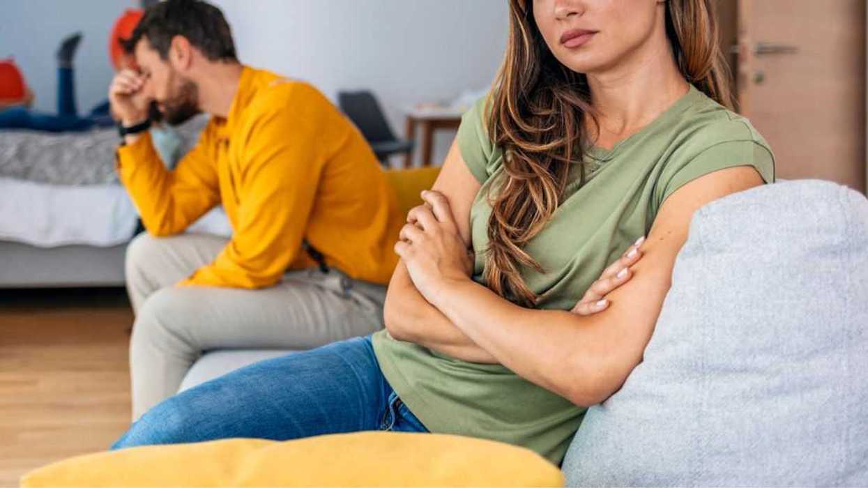 A pregnant couple sits across from one another at odds