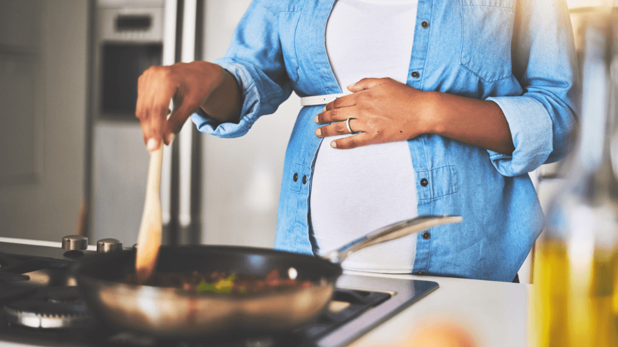 A pregnant woman cooking at a stovetop.