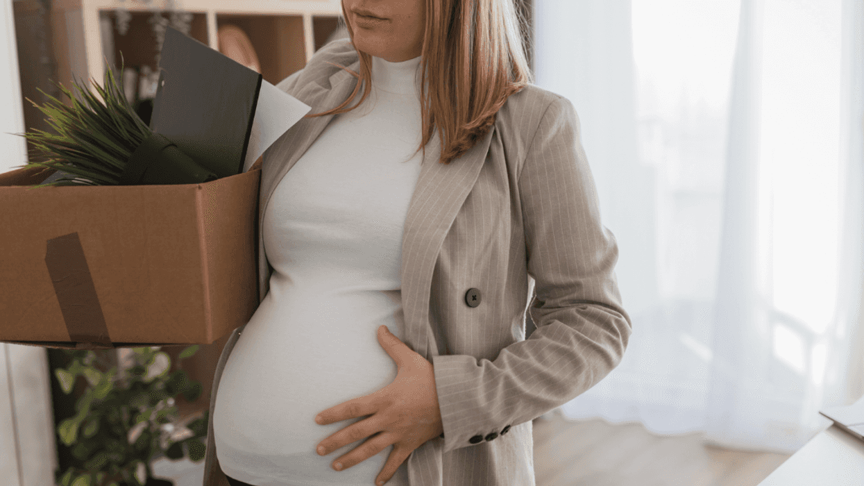 A pregnant woman holding a box with items in it.