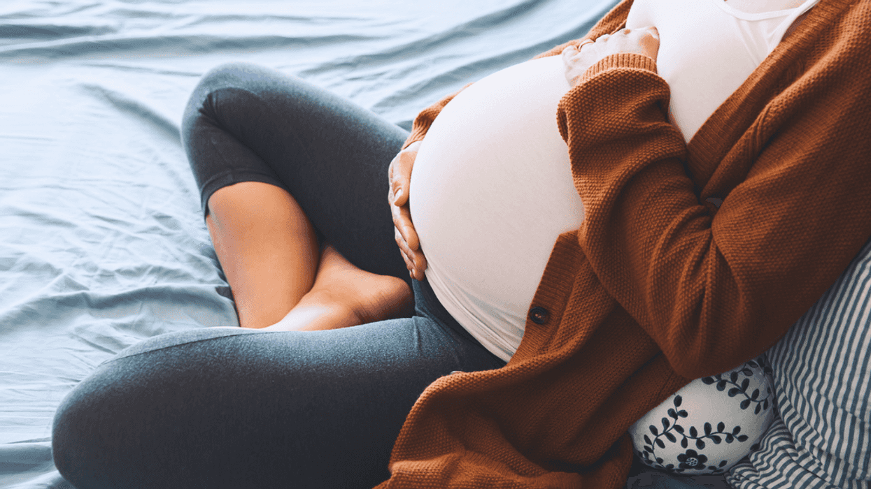 A pregnant woman lying on a bed, holding her stomach.