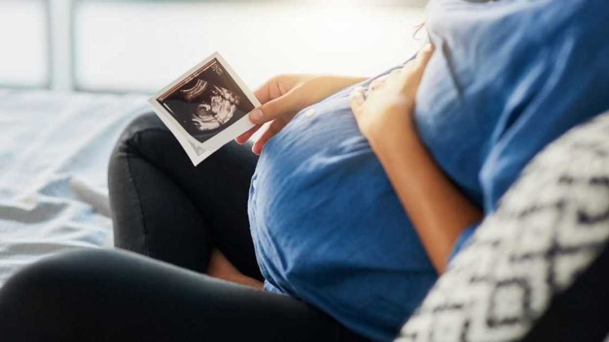 A pregnant woman sits and looks at a sonogram