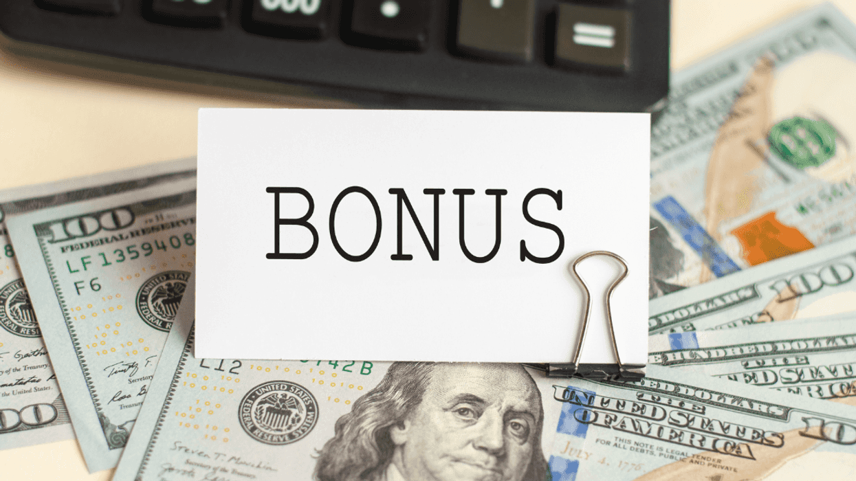 A sign saying "bonus" on top of a pile of cash.