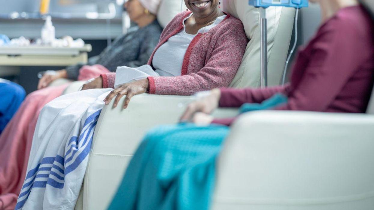 A small group of women who are battling cancer, are seen sitting in treatment chairs in an Oncology clinic. They are each dressed comfortably, and have head scarves on to keep warm as they receive their Chemotherapy treatment.