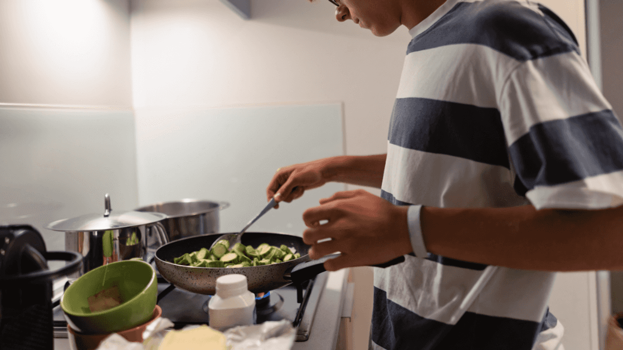 A teenage boy cooking on a stovetop