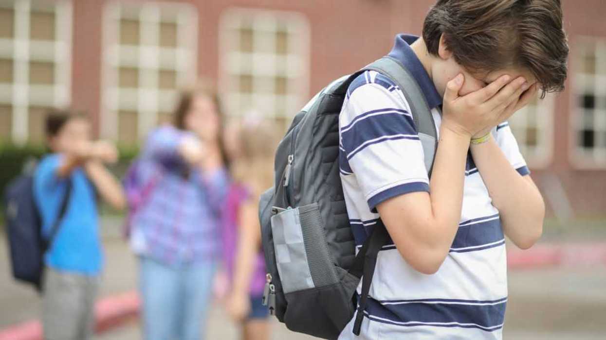 A teenage boy holds his heads in his hands