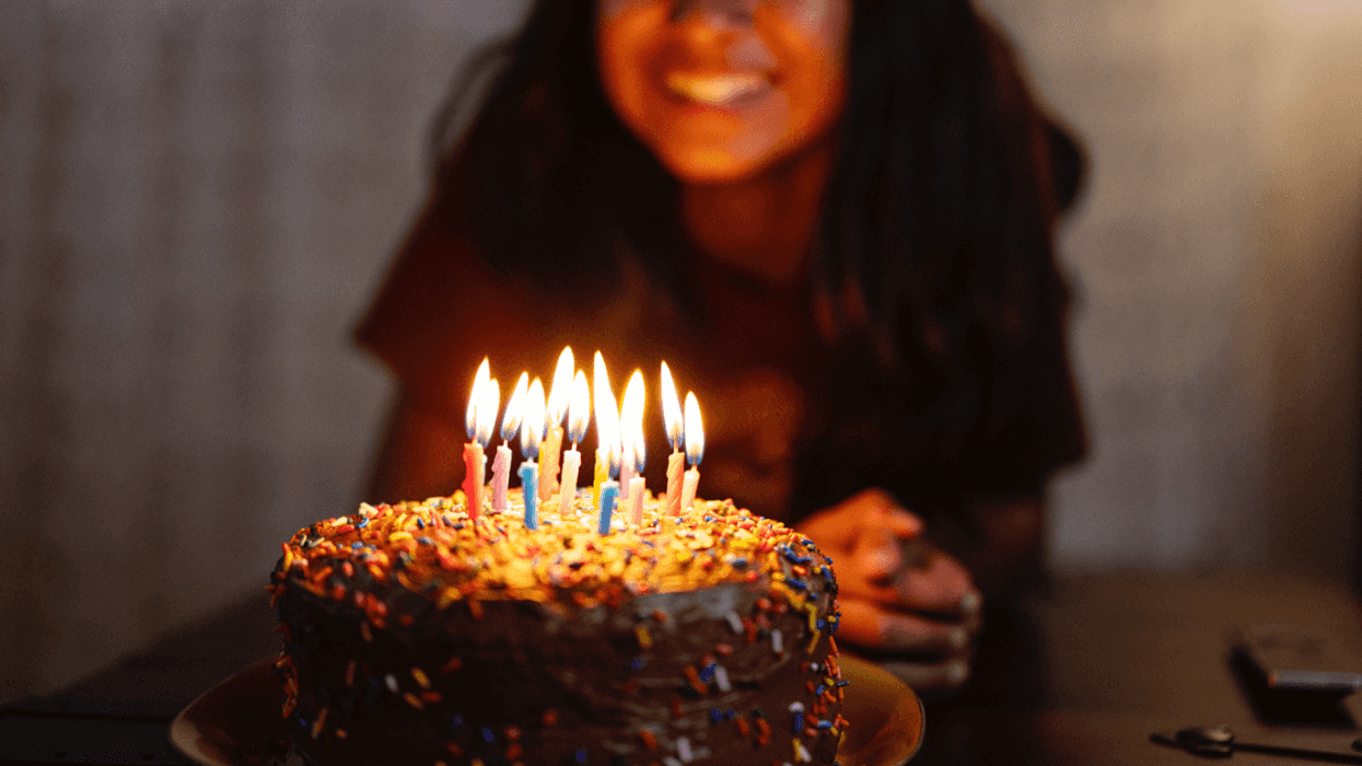 A teenage girl blowing out birthday candles.