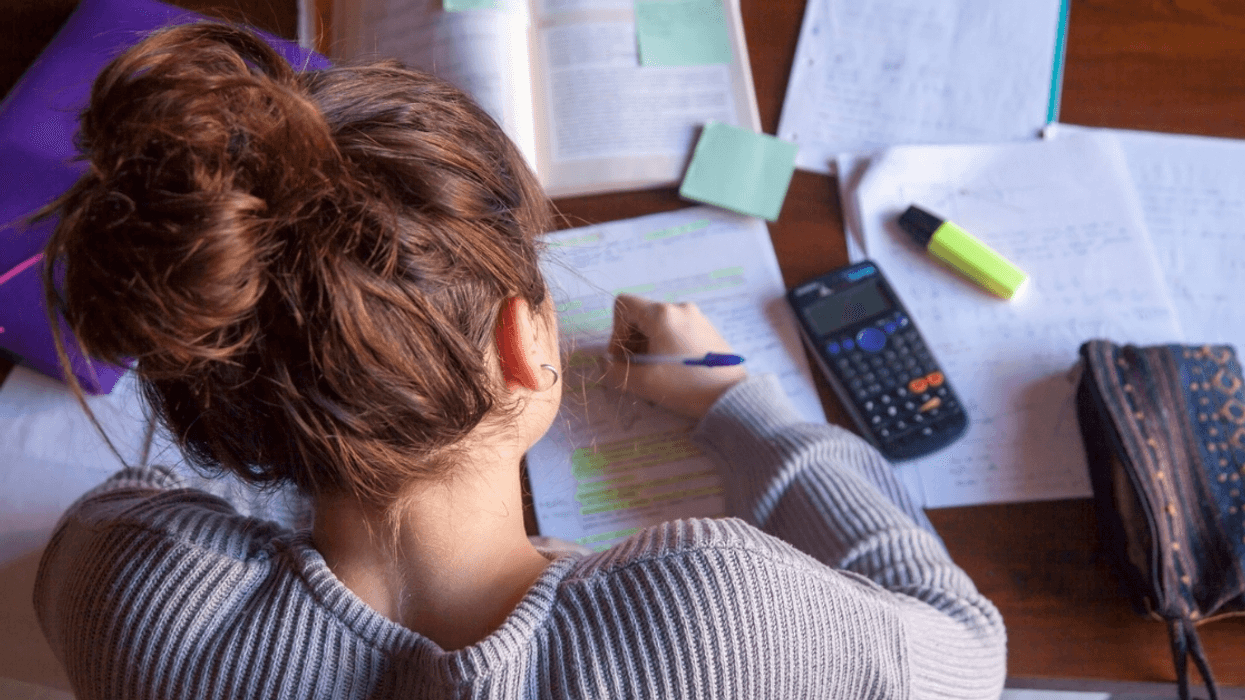 A teenage girl doing work at her desk.