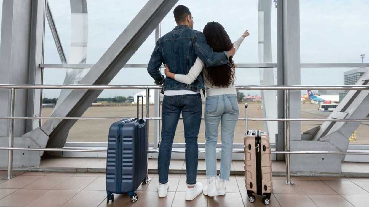 A traveling couple looks out at the tarmac