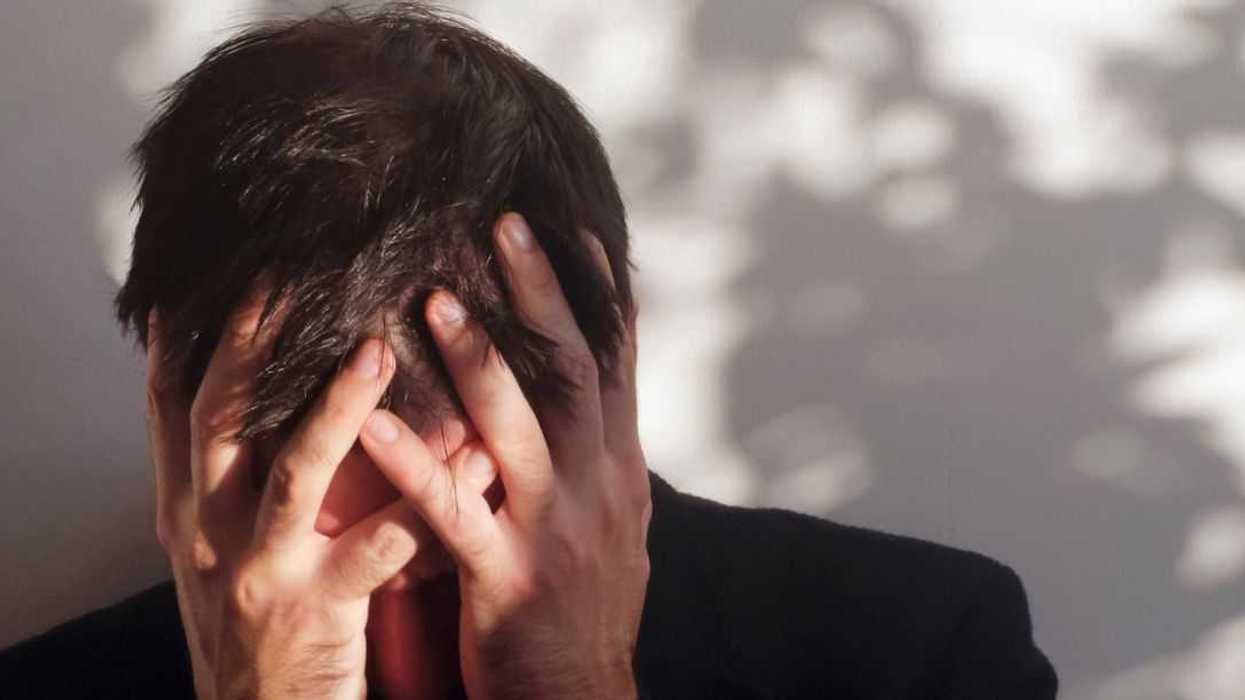 A troubled man hangs his head in his hands.