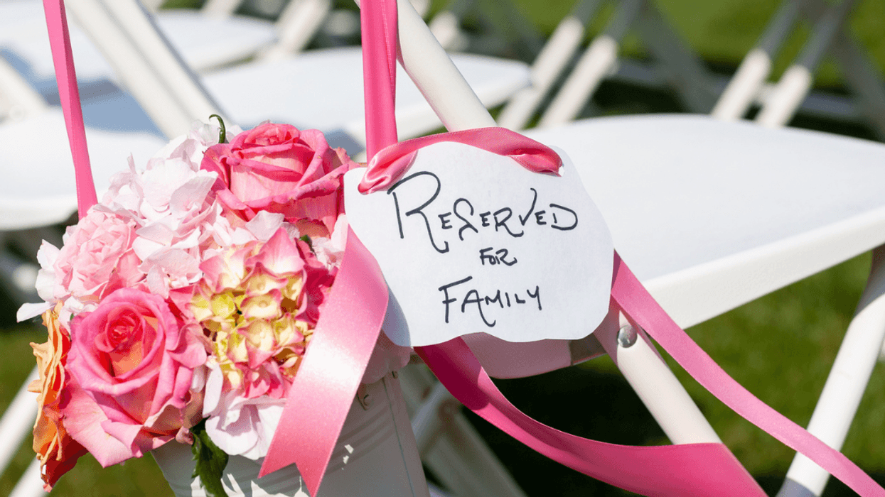 A white seat with bows, flowers and a sign saying "reserved for family" on it.
