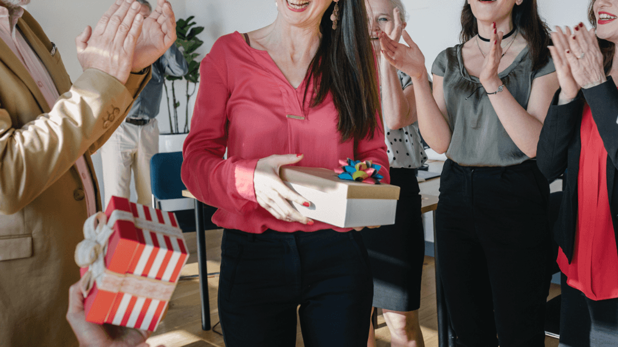 A woman being handed presents surrounded by people.