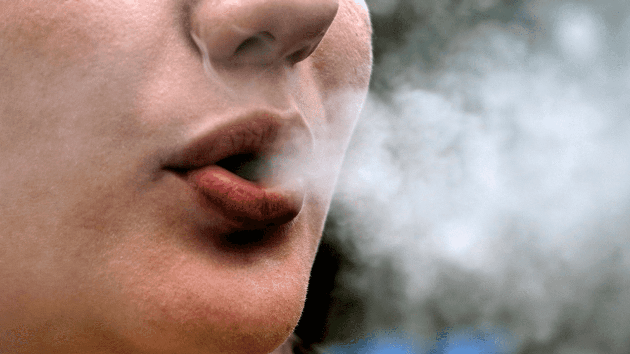 A woman blowing smoke out of her mouth.