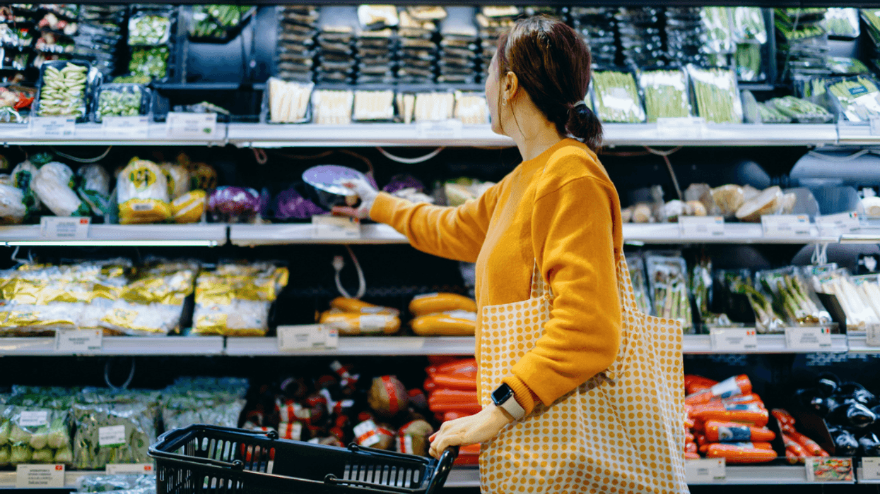 A woman buying vegetables in a grocery store.