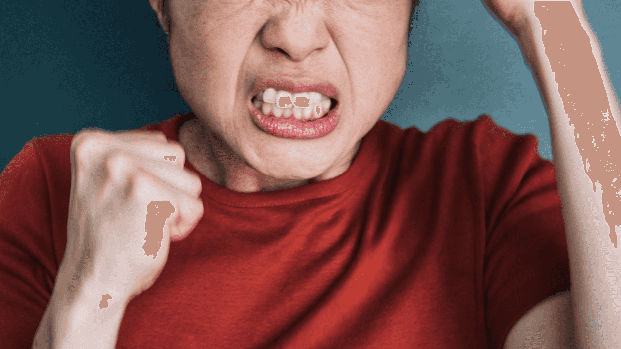 A woman clenching her fists and teeth.