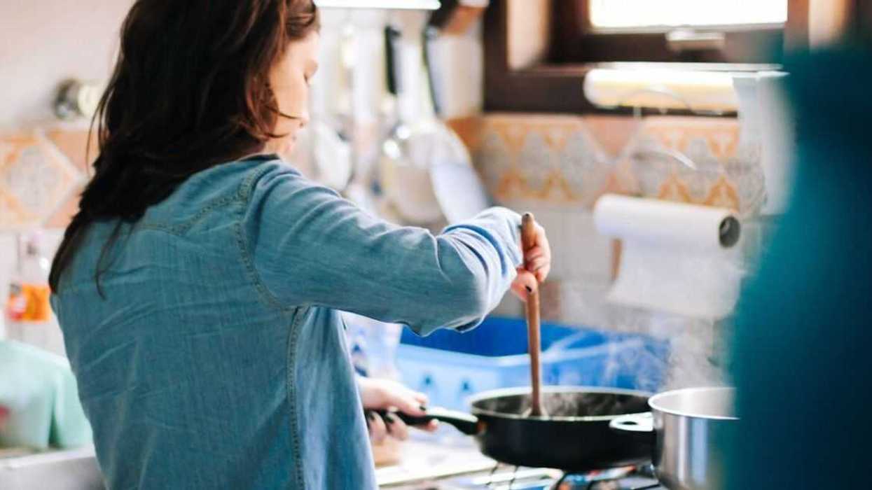 A woman cooks at the stove