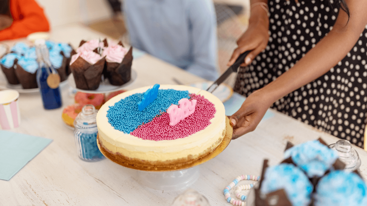A woman cutting into a gender reveal cake.