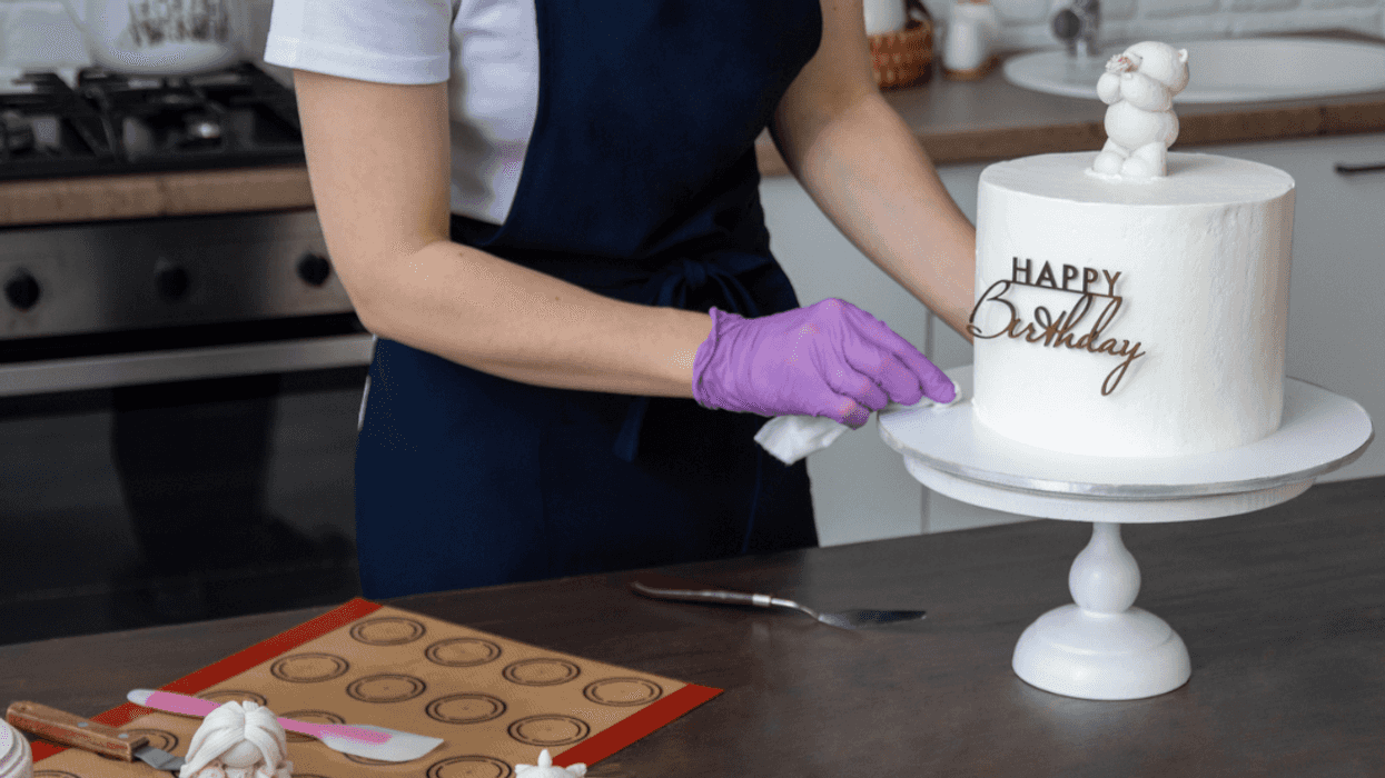 A woman decorating a cake with the words "Happy Birthday" on it.