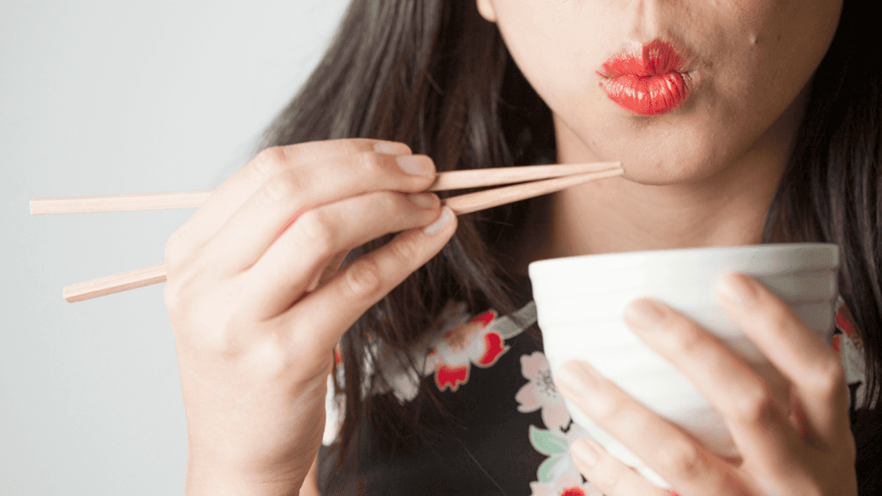 A woman eating using chopsticks.