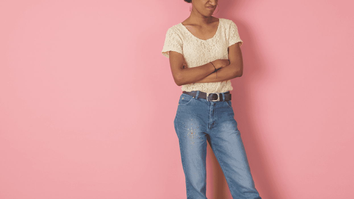 A woman folding her arms in front of a pink background