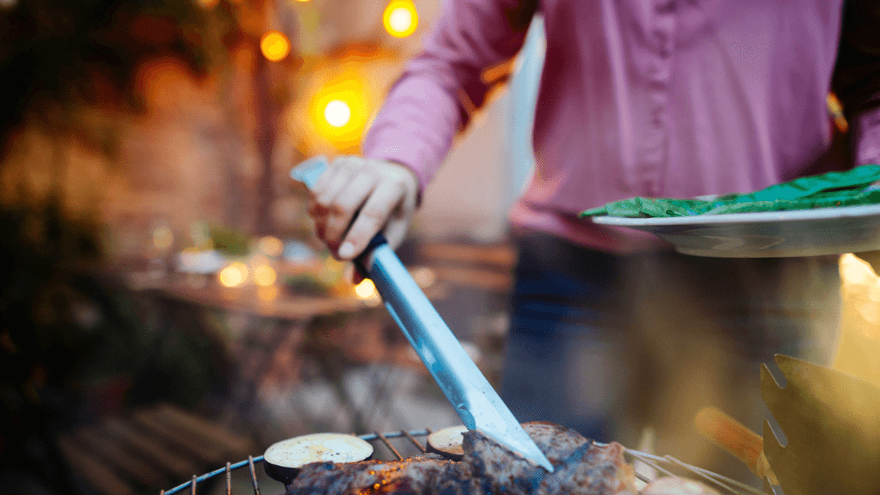 A woman grilling meat and vegetables.