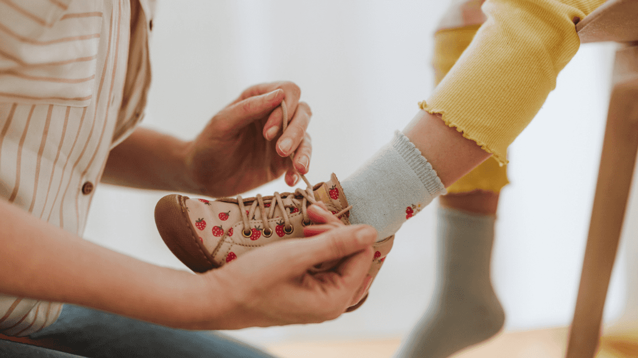 A woman helping a child put on shoes.