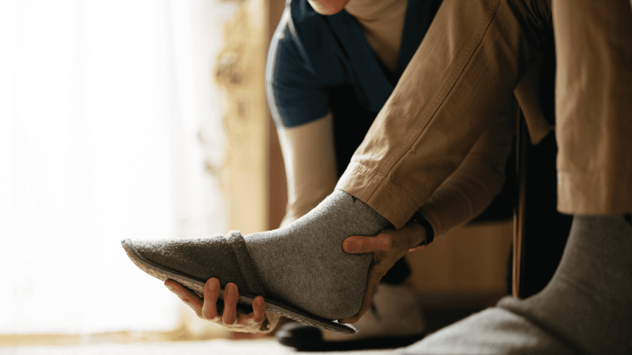 A woman helping a man take off his slippers.