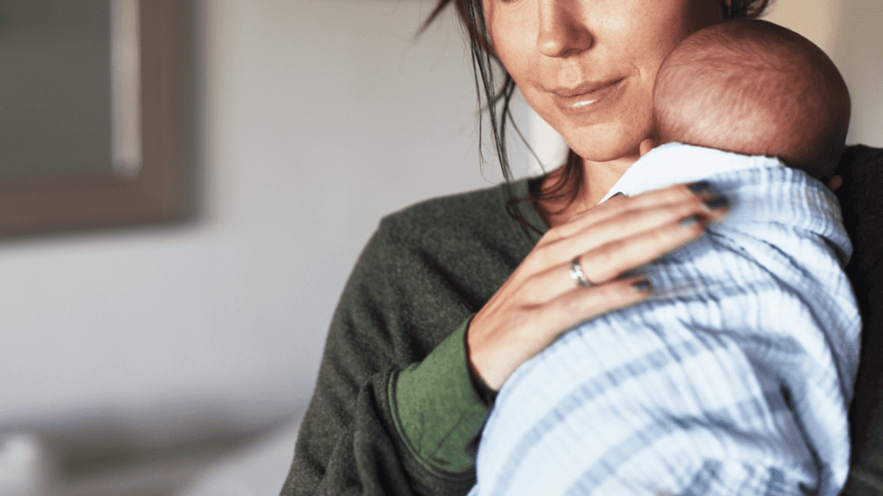 A woman holding a baby on her shoulder.