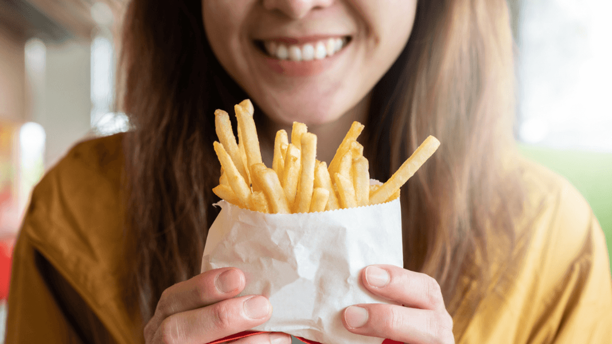 A woman holding a bag of French fries.