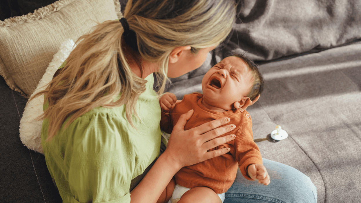 A woman holding a crying baby.