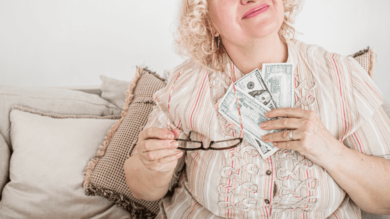 A woman holding a fan of paper bills to her chest.