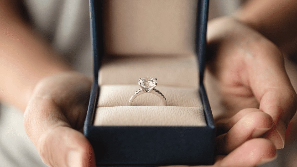 A woman holding a ring box open to reveal an engagement ring.