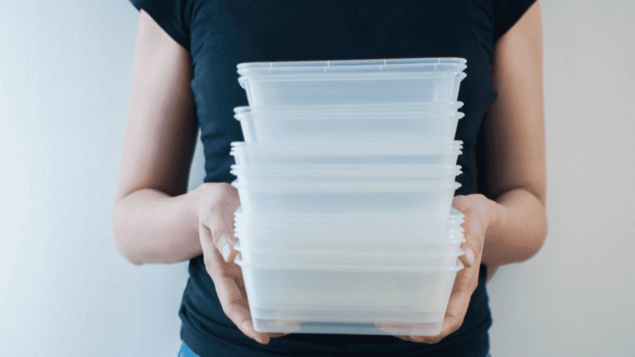 A woman holding a stack of tupperware dishes