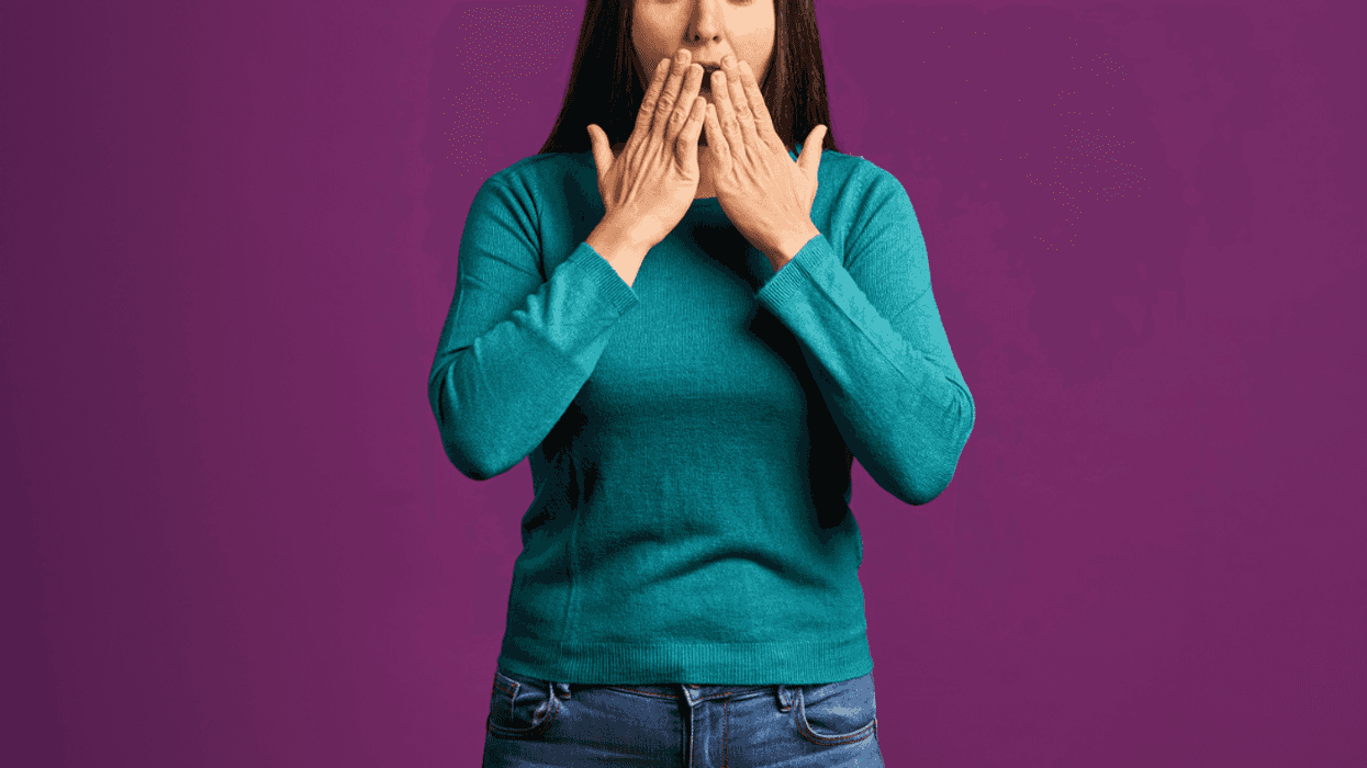 A woman holding her hands in front of her mouth.