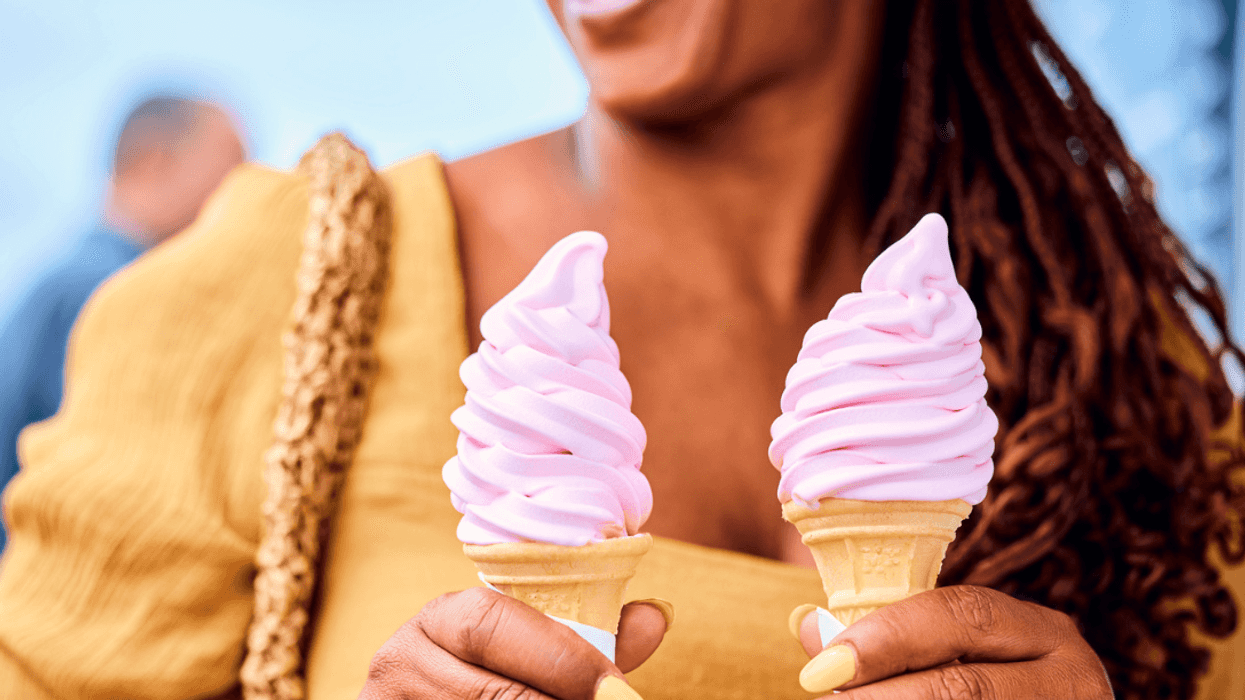 A woman holding two soft-serve ice cream cones.