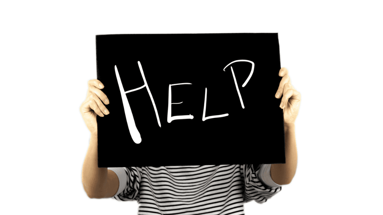 A woman holding up a help sign in front of her face.