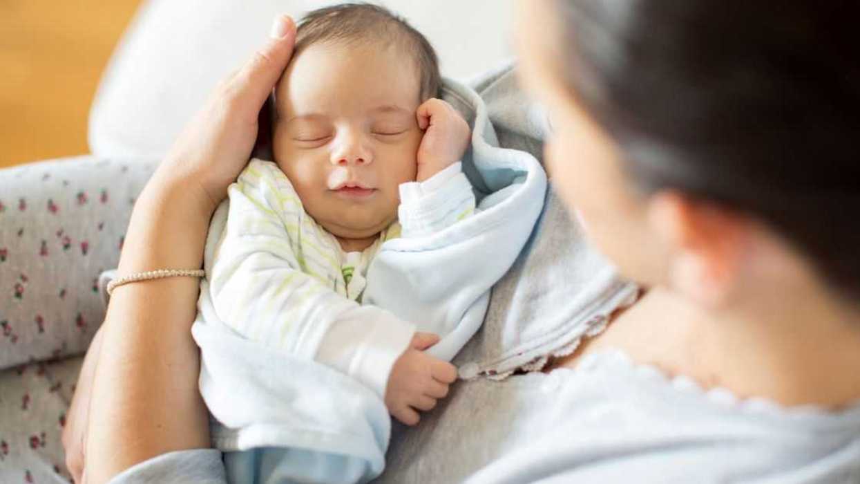 A woman holds a sleeping baby