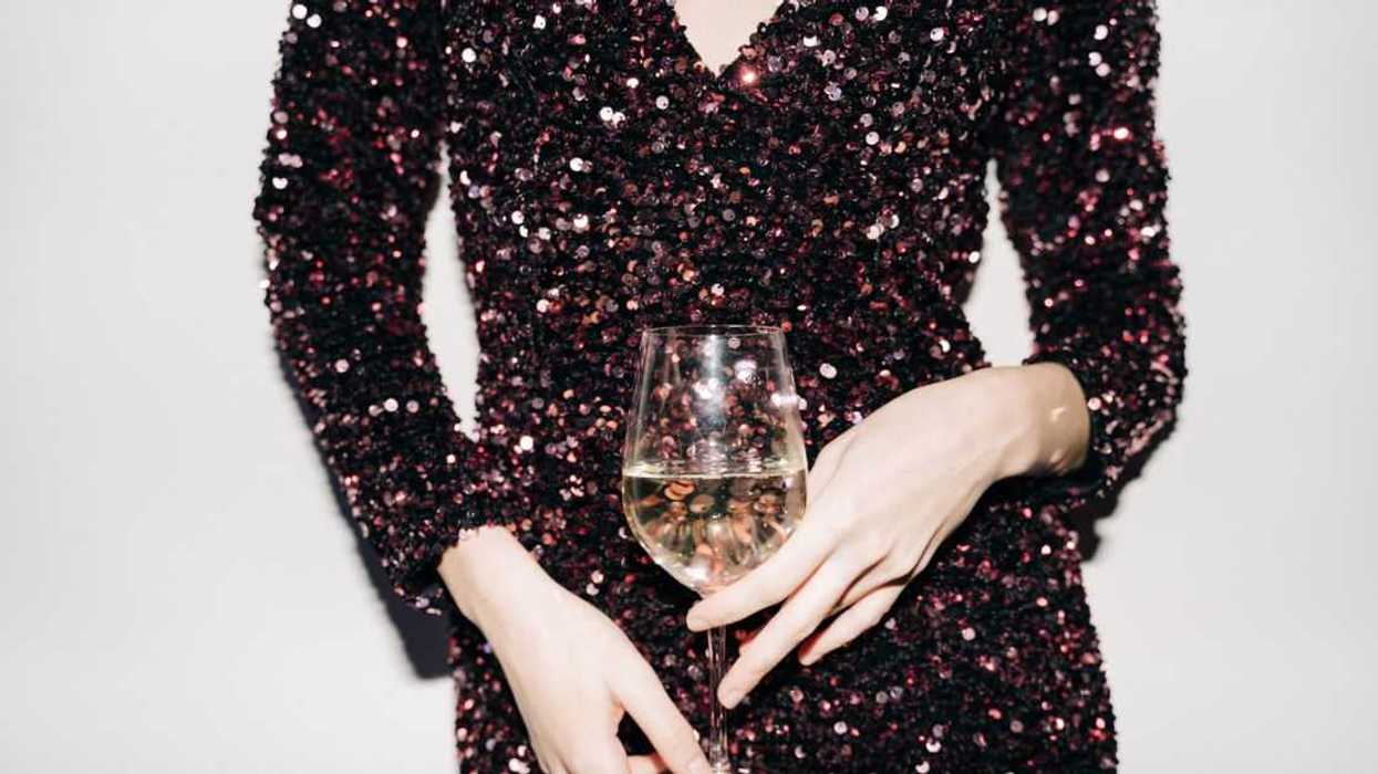 A woman in a cocktail dress with a glass of wine