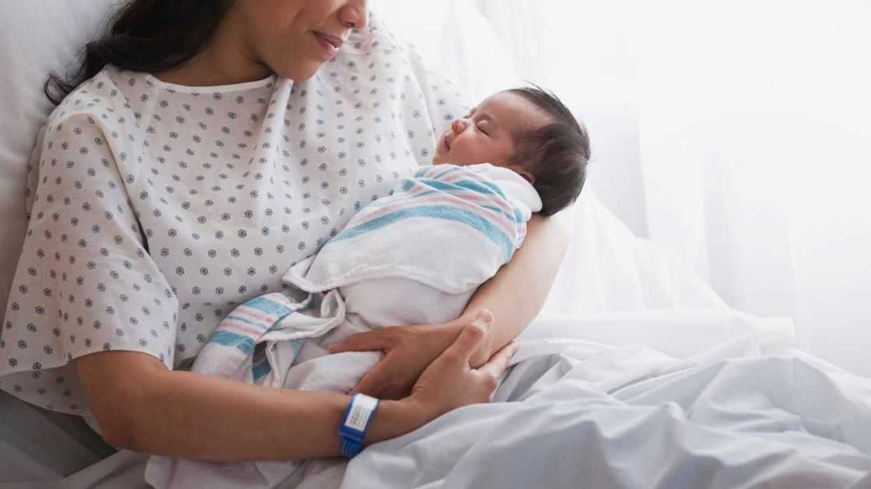 A woman in a hospital bed cradles a newborn