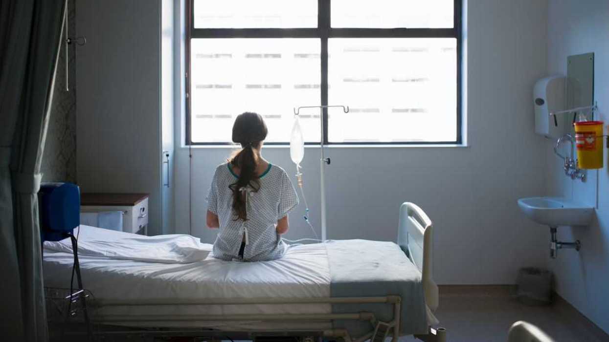 A woman in a hospital bed stares out of the widow