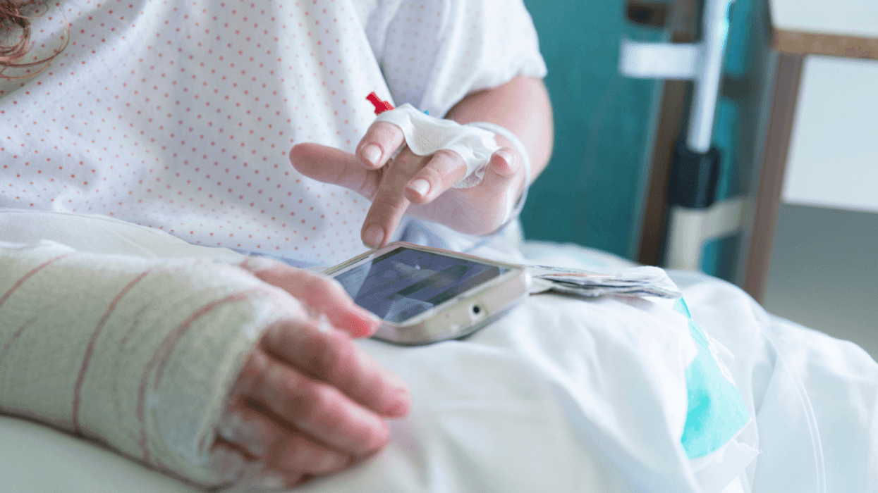 A woman in a hosptial gown and bed wearing a cast with an IV.