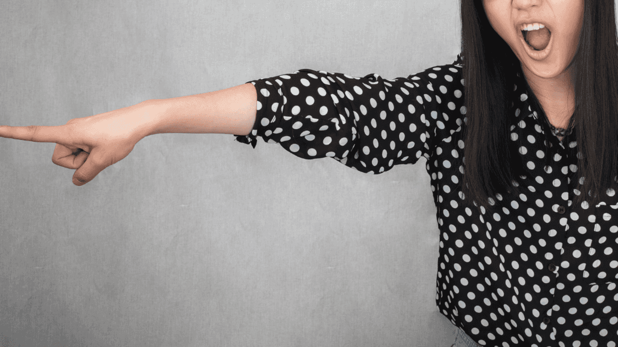 a woman in a polkadot blouse point in anger