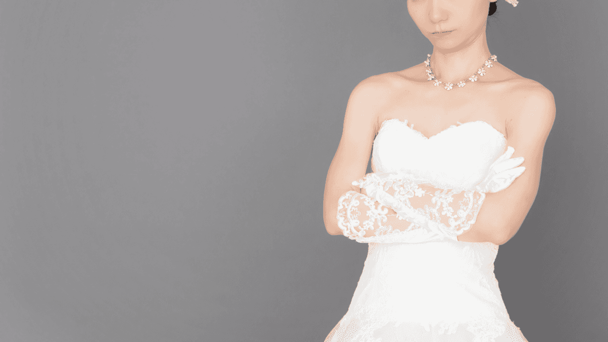 A woman in a wedding gown crossing her arms.