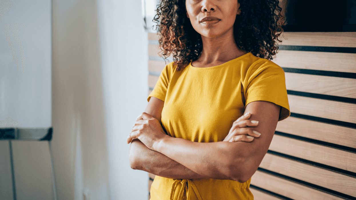 A woman in a yellow dress with her arms crossed.