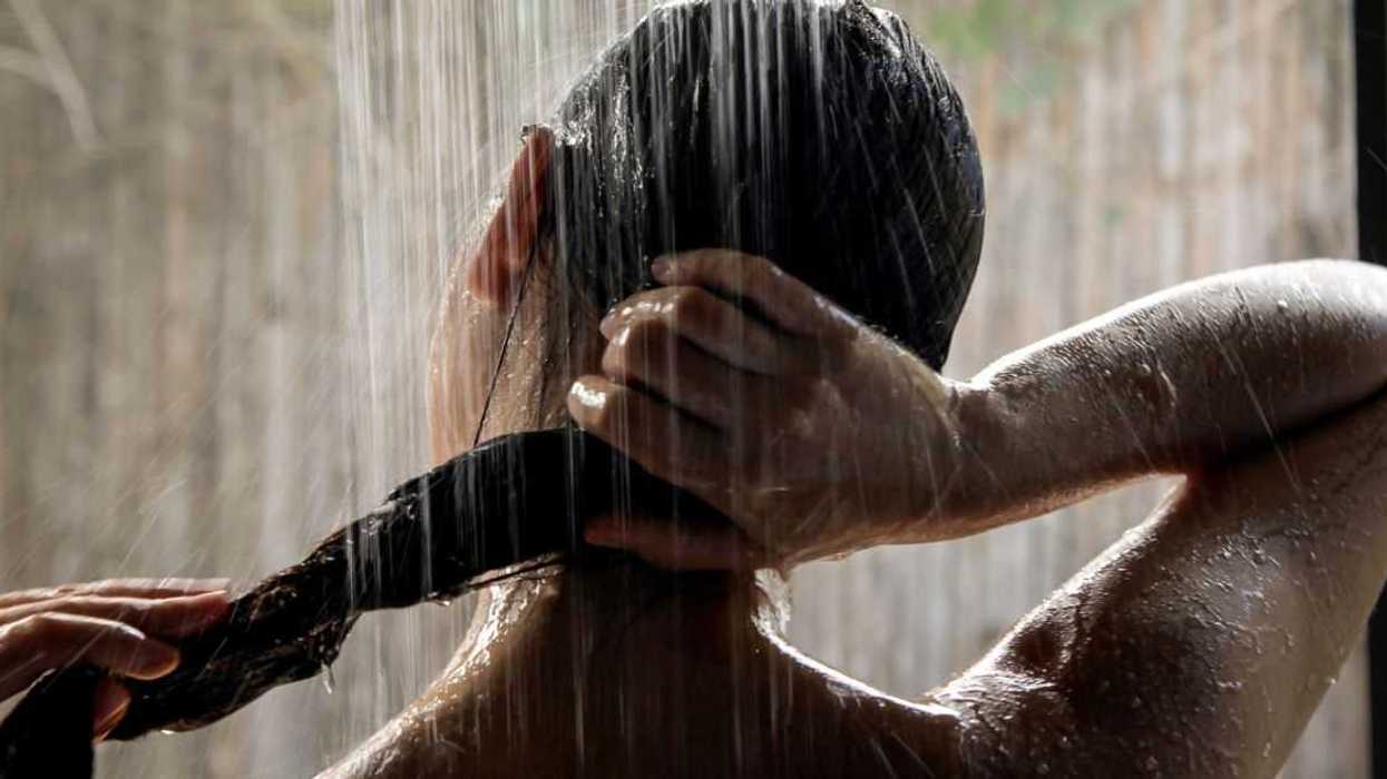 A woman in the shower extends her long hair