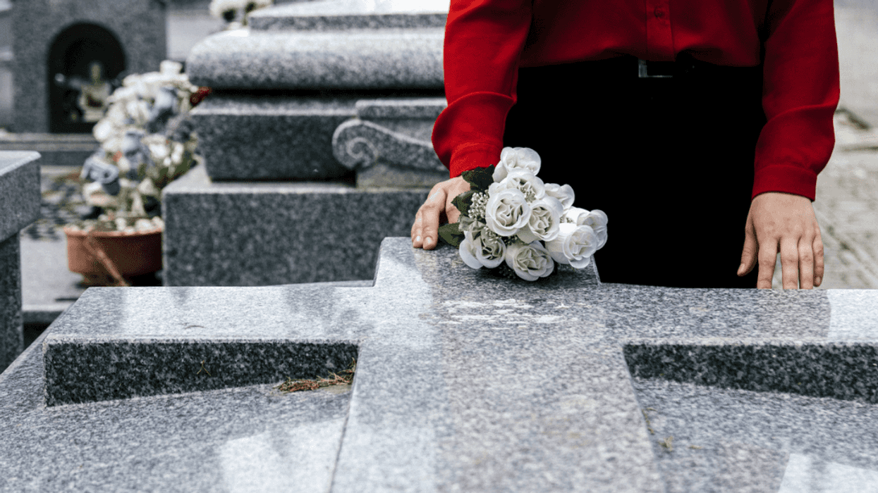 A woman laying flowers on a grave