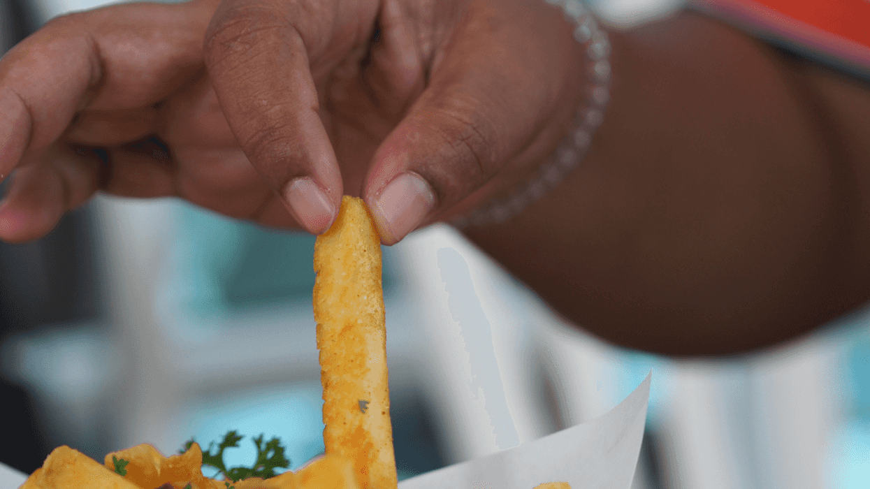 A woman lifting a french fry off a plate