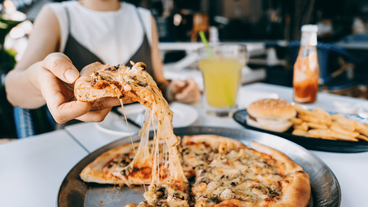 A woman lifting a slice of pizza from a whole pie